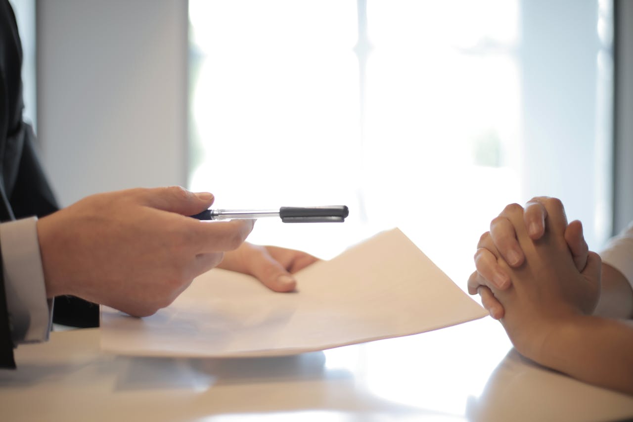 Home Close-up of a contract signing with hands over documents. Professional business interaction.